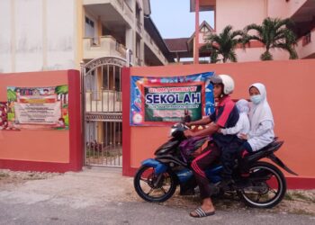 SEORANG bapa, Salahuddin Ramli menghantar dua anaknya di SK Pangkal Meleret, Tanah Merah seperti biasa pagi ini kerana tidak mendapat maklumat berkaitan penutupan sekolah di kawasan yang dikenakan PKP di Kelantan. - UTUSAN/BAHRUDDIN HATTA