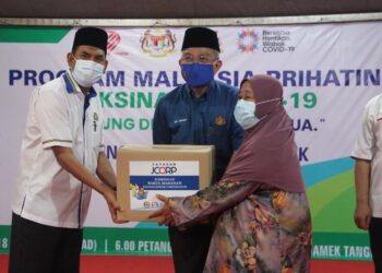 ADHAM Baba (tengah) menyampaikan sumbangan sara hidup kepada sebahagian penduduk sempena Program Malaysia Prihatin Oleh Menteri Kesihatan di Perkarangan Masjid Jamek Bandar Tangkak, Johor. - UTUSAN/NUR ALINA HASSAN