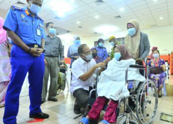 WAN ROSDY Wan Ismail (tengah) berbual bersama seorang penerima vaksin yang berusia 60 tahun ke atas di Wisma Belia Indera Mahkota di Kuantan, Pahang. 
UTUSAN/SHAIKH AHMAD RAZIF