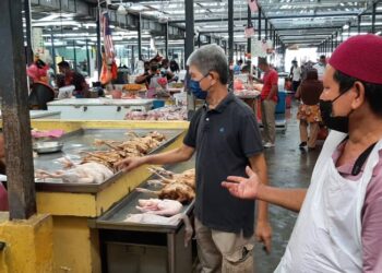 PENIAGA sempat berbincang mengenai harga siling ayam yang ditetapkan pada harga RM7.90 di Pasar Besar Melaka. - UTUSAN/AMRAN MULUP