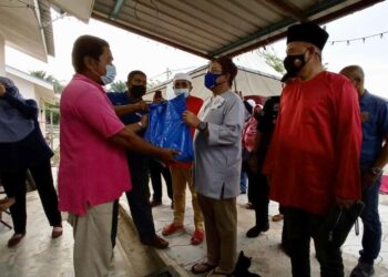 ABDUL Latiff Ahmad (dua dari kanan) menyerahkan sumbangan kepada salah seorang penduduk pada Majlis Penyampaian Bakul Makanan di Taman Sinar Sedili, Kota Tinggi, Johor. -UTUSAN/MASTURAH SURADI.