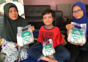 MUHAMAD Safar (tengah) mengusahakan perniagaan Ketupat Mini Muhammad bersama Nor Azlia (kanan) dan Hattyca Karmon di Kampung Parit Haji Hashim, Simpang Renggam, Kluang di Johor. -UTUSAN/NUR NABILAH RAHMAT