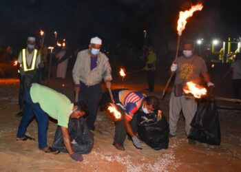 ANTARA komuniti setempat yang menyertai Program Bersih Pantai Ramadan selepas solat sunat tarawih dengan masing-masing membawa obor api di Pantai Kelulut, Marang, Terengganu. - UTUSAN/PUQTRA HAIRRY ROSLI