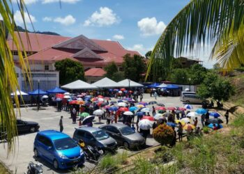 IBU bapa dan murid terpaksa berpayung kerana cuaca panas terik ketika menunggu proses ujian calitan Covid 19 di Klinik Kesihatan Beserah, di Kuantan, Pahang. 
UTUSAN/KHAIRULMIZAN YAHYA