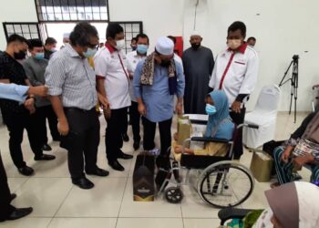 SULAIMAN Md. Ali (tiga dari kanan) menyampaikan sumbangan Ramadan kepada salah seorang penerima, Suhaila Mahad (berkerusi roda) sambil diperhatikan Abu Bakar Mohd. Diah (dua dari kiri) dan Mohamad Ali Mohamad di Japerun Klebang, Melaka. - UTUSAN/AMRAN MULUP