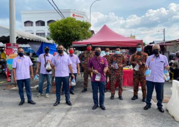 MOHD.  Ismail Mohd. Yunus (tengah) mengagihkan bubur lambuk kepada pengunjung Bazar Ramadan Teluk Intan semalam. -  UTUSAN/IHSAN JBPM