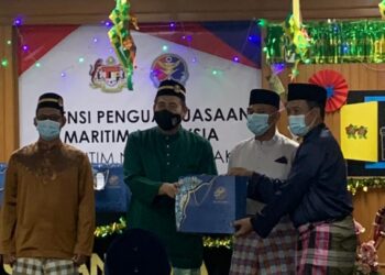 SHAHRIZAN Raman (dua dari kiri) menyampaikan bungkusan raya kepada anggotanya yang bertugas semasa hari raya pada majlis pejabat Maritim Malaysia Perak di Lumut hari ini. - UTUSAN