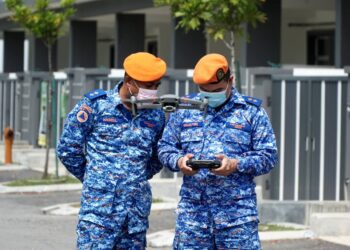 AHMAD Muafiri Muhamad (kanan) dan Muhammad Hasrul Hashim  membuat pemantauan pematuhan SOP PKPD menggunakan dron di kawasan Klebang, Ipoh hari ini. - UTUSAN/ZULFACHRI ZULKIFLI.