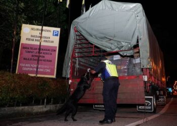 ANGGOTA Unit K9 IPK Perak memeriksa kenderaan berat yang melalui SJR menggunakan anjing pengesan di Jalan Abdul Raof, Parit Buntar. - UTUSAN/ZULFACHRI ZULKIFLI