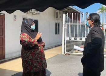 NORJANNAH  RUSLI yang dituduh kerana menyebar berita tidak benar menggunakan aplikasi WhatsApp berbincang dengan peguamnya di luar mahkamah di Mahkamah Sesyen Kangar, Perlis hari ini.- UTUSAN/NAZLINA NADZARI