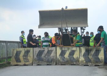 NOORZAINY Mohd. Noor memerhatikan kerja-kerja pemasangan penghadang konkrit di lorong tikus di Perai, Pulau Pinang bagi menghalang orang ramai merentas daerah tanpa kebenaran.