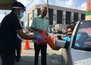 GHAZALE Muhammad (tengah) menyerahkan barangan PST secara dalam talian kepada pembeli di Japerun Rim, Jasin, Melaka. - UTUSAN/DIYANATUL ATIQAH ZAKARYA