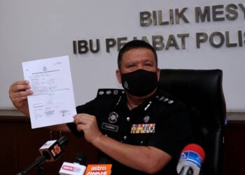 A. ASMADI Abdul Aziz menunjukkan dokumen rentas negeri palsu yang dikesan dalam pemeriksaan ke atas sebuah bas persiaran di SJR Plaza Tol Ipoh Selatan pada sidang akhbar di IPD Ipoh hari ini. - UTUSAN/ZULFACHRI ZULKIFLI