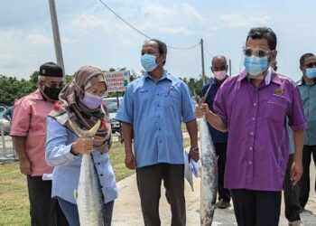 CHE Abdullah Mat Nawi (kanan) bersama hasil tangkapan ikan yang didaratkan nelayan di Pasar Pulau Gajah, Kota Bharu, Kelantan hari ini. - UTUSAN/YATIMIN ABDULLAH