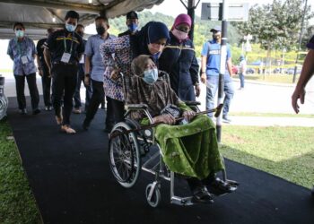 NORAINI (tengah) membantu warga emas yang hadir bagi mendapatkan suntikan vaksin di PPV UiTM Puncak Alam, Kuala Selangor hari ini. UTUSAN/ZULFADHLI ZAKI