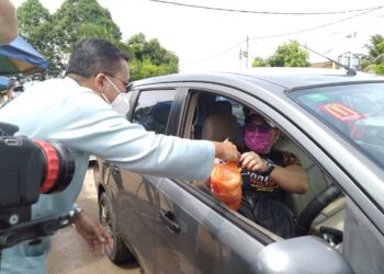 MOHD. RAFIQ Naizamohideen (kiri) menyampaikan sumbangan barangan keperluan asas secara pandu lalu kepada pengunjung Kedai Prihatin Rakyat di Taman Rambai Jaya,  Bukit Rambai, Melaka. - UTUSAN/MUHAMMAD SHAHIZAM TAZALI