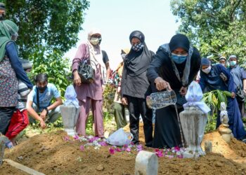 ZAILAH Jusoh menyiram air mawar pada pusara bapanya, Jusoh Muda di Tanah Perkuburan Islam Makam Lama, Cabang Tiga di Kuala Terengganu hari ini. -UTUSAN/PUQTRA HAIRRY ROSLI