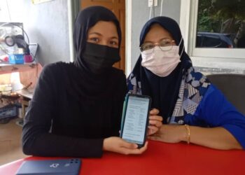 SITI NUR FATEHAH Zulkafli (kiri) bersama ibunya, Mariani Ismail menunjukkan keputusan peperiksaan Sijil Pelajaran Malaysia menerusi portal Lembaga Peperiksaan Malaysia di Felda Kota Gelanggi Dua di Jerantut, Pahang. - UTUSAN/HARIS FADILAH AHMAD