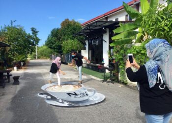 PELANGGAN yang mengambil pesanan tidak melepaskan peluang bergambar dengan mural secawan kopi di kedai Nusuk Cafe di Taman Chonang Jaya di Kuala Nerus. - UTUSAN/TENGKU DANISH BAHRI TENGKU YUSOFF