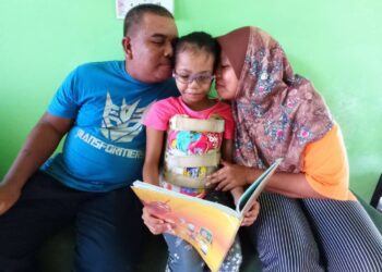 NUR Hawa Syafiah Rosli bersama bapa, Rosli Mohd. Said dan ibunya, Marhana Mohd. Kamso terpaksa memakai baju khas selama 22 jam sehari untuk menyokong tulang belakang agar tidak membengkok akibat menghidap sindrom goldenhar. – UTUSAN/MASTURAH SURADI