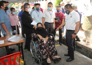 TAKIYUDDIN Hassan (kanan) berkata sesuatu kepada seorang warga emas yang hadir menerima suntikan vaksin di PPV Dewan Perniagaan Cina, Jalan Kebun Sultan, Kota Bharu. - UTUSAN/ROHANA MOHD. NAWI