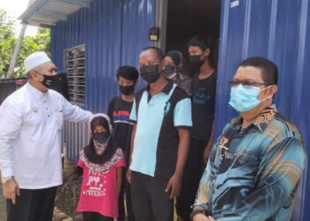 RAZMAN Zakaria (kiri) melawat lima sekeluarga yang tinggal dalam kabin kontena setelah rumah mereka terbakar di Semanggol dekat Bagan Serai hari ini.