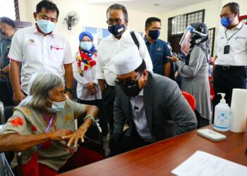 SULAIMAN Md. Ali menyantuni salah seorang penerima vaksin di Program Outreach Vaksinasi DUN Kuala Linggi di Kompleks Japerun Kuala Linggi, Melaka. - UTUSAN/DIYANATUL ATIQAH ZAKARYA