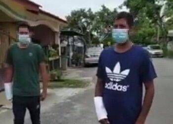 TANGKAP layar rakaman video yang memaparkan dua lelaki warga asing menutup lengan mereka dengan kertas putih yang berjalan di sebuah kawasan taman perumahan. - MEDIA SOSIAL