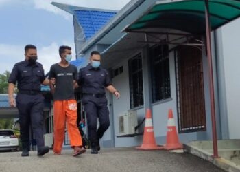 M. Devandran dibawa anggota polis bagi didakwa di Mahkamah Seksyen Kuala Pilah atas dua pertuduhan membabitkan khianat dengan api sehingga menyebabkan dua buah kenderaan terbakar dalam kejadian di rumah ibu mentuanya di Kampung Indah, Jempol pada 12 Julai lalu. - UTUSAN/NOR AINNA HAMZAH