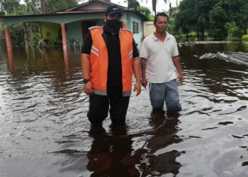 MUHAMMAD Taqiuddin Cheman (kiri) bersama penduduk yang rumahnya dilanda banjir melihat kawasan sekitar yang masih digenangi air akibat banjir di Kampung Jawa Ulu, Ayer Baloi, di Pontian, Johor.