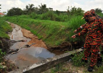 YAHAYA Madis (kanan) menunjukkan oil boom yang dipasang bagi menyekat sisa buangan daripada terus mengalir di sungai berhampiran Kampung Baru Seri Aman, Seelong di Kempas, Johor. -UTUSAN/RAJA JAAFAR ALI