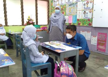 MOHD. RADZI Md. Jidin (kanan) berbual dengan seorang murid Tahun 1 semasa melawat SK Ayer Molek di Ayer Molek, Melaka. - UTUSAN/MUHAMMAD SHAHIZAM TAZALI