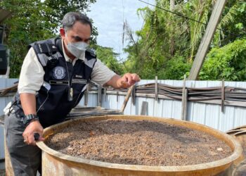 MOHD. Wazir Khalid menunjukkan tong gentian kaca yang digunakan untuk memproses perapan yang didapati terlalu buruk dalam operasi di sebuah kilang pemprosesan kicap di Butterworth, Pulau Pinang hari ini.