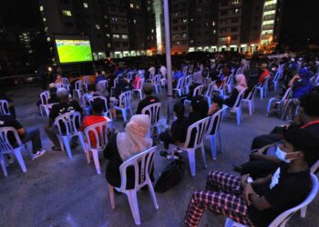 Kira-kira 300 penduduk menyaksikan perlawanan akhir Piala Malaysia antara JDT dan KL City menerusi skrin besar di Pangsapuri Desa Kampung Hajah Hasnah Johor Bahru, malam ini.- UTUSAN/RAJA JAAFAR ALI