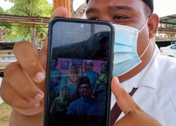 MOHD. Zulhelmi Ramli menunjukkan gambar kenangan mereka sekeluarga bersama arwah bapanya, Ramli Ibor yang terkorban dalam kemalangan bersama kelindannya di Segamat, Johor.