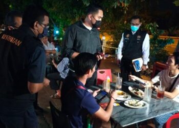 MUHAMAD AKMAL Saleh (tengah) bertanyakan sesuatu kepada pelanggan sebuah kedai makan di Ayer Keroh, Melaka ketika Operasi Khas Penguatkuasaan SOP PPN Fasa 4 dan PPKHT. - UTUSAN/DIYANATUL ATIQAH ZAKARYA