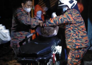 ANGGOTA bomba membantu mangsa patah kaki selepas rumahnya dihempap pokok tumbang di Kampung Ara Payung, Batu Gajah hari ini. - UTUSAN/IHSAN JBPM PERAK