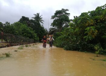 KANAK-KANAK menunggang basikal meredah banjir di Kampung Pasir Raja di Dungun. - UTUSAN/NIK NUR IZZATUL HAZWANI NIK ADNAN