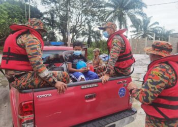 ANGGOTA bomba membantu mangsa banjir di Batu 9, Changkat Jong Teluk Intan berpindah ke PPS hari ini. - UTUSAN/IHSAN JBPM PERAK