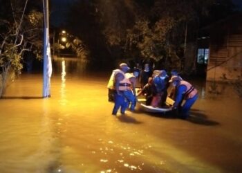 ANGGOTA APM  memindahkan mangsa banjir dari Kampung Kuala Slim ke pusat pemindahan sementara di Sekolah Kebangsaan Kuala Slim, Slim River.  - UTUSAN/IHSAN APM