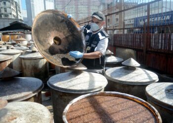 MOHD. WAZIR Khalid menunjukkan tong gentian kaca yang telah rosak dan pecah di bahagian penutup namun masih digunakan untuk memproses perapan kacang soya di sebuah kilang pemprosesan kicap di Jalan Patani, Georgetown, Pulau Pinang. - UTUSAN/IQBAL HAMDAN