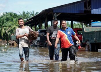 PENDUDUK meredah air banjir yang melanda kawasan mereka di Kampung Batu 7 1/2, Jalan Changkat Jong, Teluk Intan hari ini. - UTUSAN/ZULFACHRI ZULKIFLI