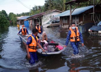 ANGGOTA Angkatan Pertahanan Awam (APM) membantu penduduk yang terjejas banjir di Lorong Mesra, Batu 7 1/2, Jalan Changkat Jong, Teluk Intan petang tadi. - UTUSAN/ZULFACHRI ZULKIFLI