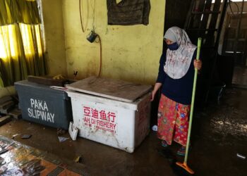 PENDUDUK Kampung Ban Ho di Kemaman membersihkan kediaman mereka selepas dibenarkan pulang dari pusat pemindahan sementara (PPS) hari ini susulan banjir yang sudah pulih. - NIK NUR IZZATUL HAZWANI NIK ADNAN