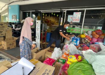 AHMAD SAFIUDDIN Ahmad Razak dan Nurul Erwani Zaidi menyusun barang sumbangan yang turut diterima daripada rakyat Melaka untuk disalurkan kepada mangsa banjir. - UTUSAN/DIYANATUL ATIQAH ZAKARYA