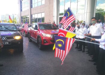 NOR Hizwan Ahmad (kanan) mengangkat Jalur Gemilang sebagai simbolik pelepasan misi bantuan mangsa banjir PBM di Hotel Wyndham Acmar, Bukti Raja di Klang, Selangor hari ini. - UTUSAN ABDUL RAZAK IDRIS