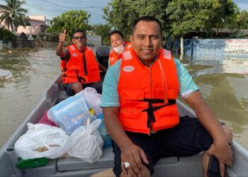 M. PARAMASIVAN (belakang,kiri) bersama Nor Shabudin (depan) menaiki bot untuk mengedar bungkusan makanan kepada mangsa banjir yang masih berada di rumah mereka di Taman Sri Muda, Seksyen 25 di Shah Alam, Selangor.