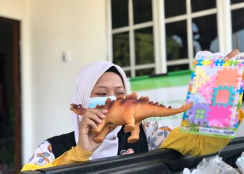 NUR Auni Arina Mohd. Amir memasukan barang permainan ke dalam pek untuk disumbangkan kepada kanak-kanak mangsa banjir di PPS Teluk Intan di Tadika Kaffah Kids di Tronoh hari ini. - UTUSAN/LIYANA RAMLI