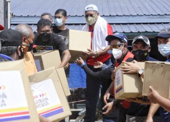 ANNUAR Musa (dua dari kanan) turut sama membantu menyerahkan bantuan bantal dan tilam kepada mangsa terjejas banjir di Kampung Chennah, Titi, Jelebu hari ini. - UTUSAN/MOHD. SHAHJEHAN MAAMIN