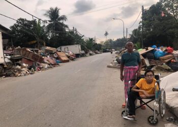 MUHAMMAD Rosli (kanan) kongsikan gambar sampah yang bertimbun di tepi jalan dikumpulkan oleh penduduk Kampung Tengah selepas kawasan berkenaan dilanda banjir di Puchong, Selangor.